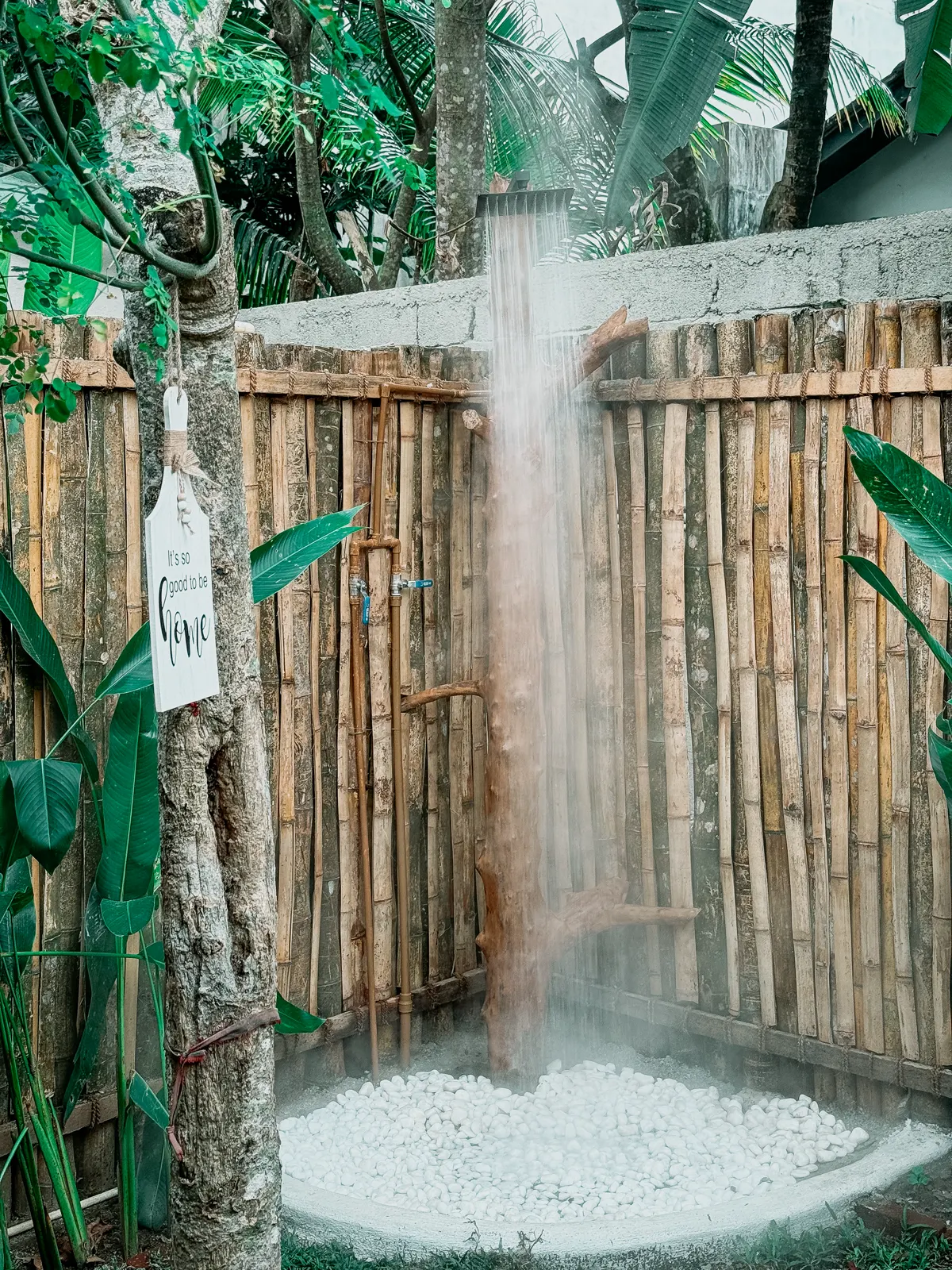Tropical outdoor shower surrounded by bamboo and greenery at Kickin’ Surf Lodge