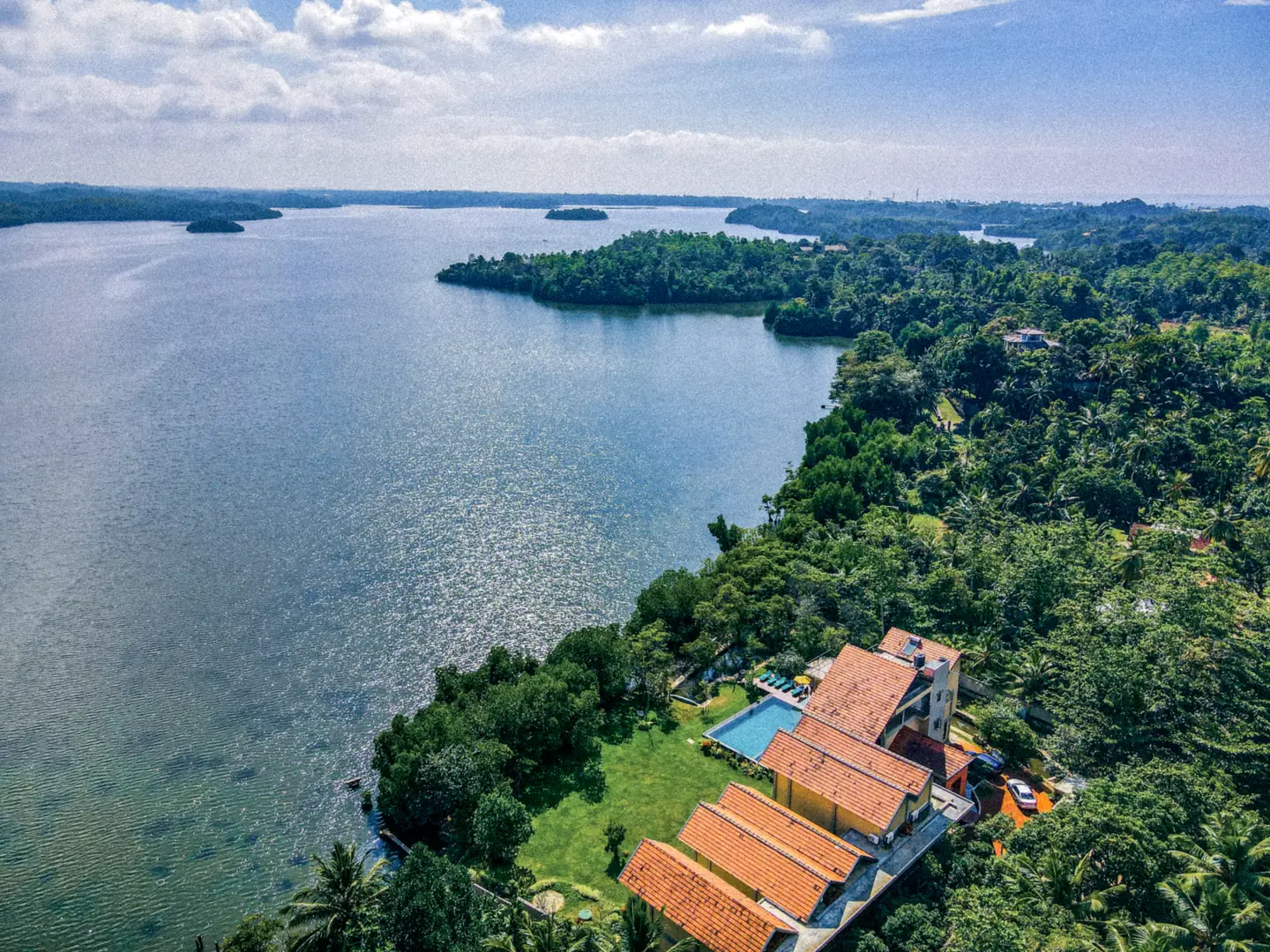 Aerial photograph of Zen Koggala’s terracotta-roofed buildings, pool and garden beside Koggala Lake